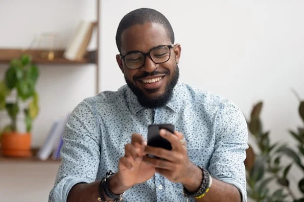 a man smiling while holding a phone
